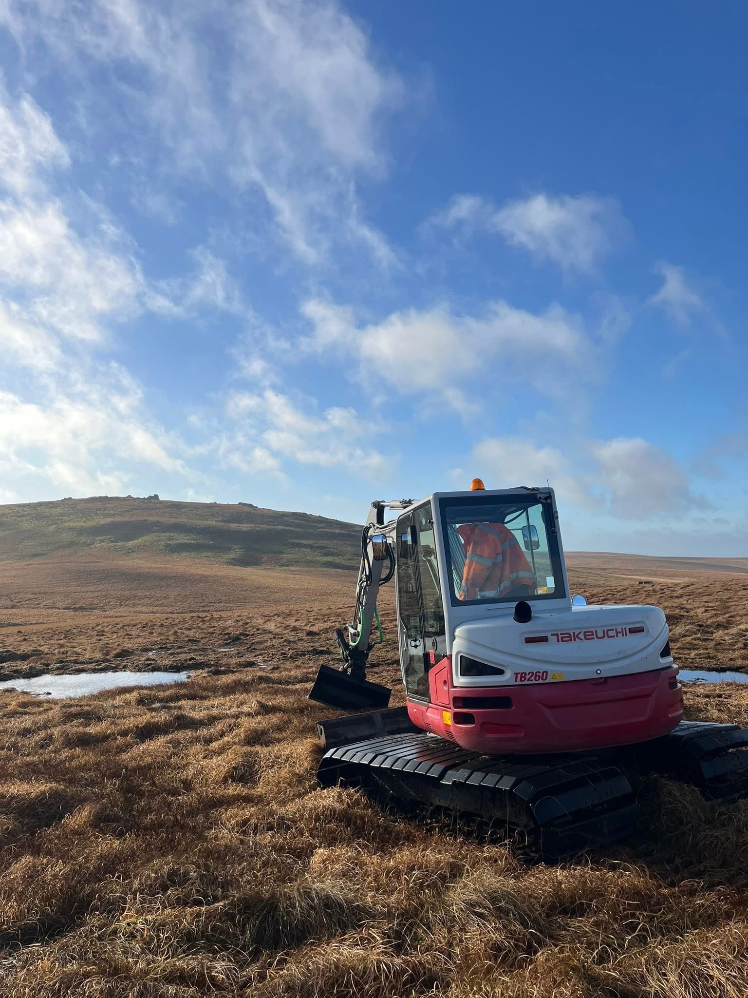 Excavator on Dartmoor moorland during peatland restoration project